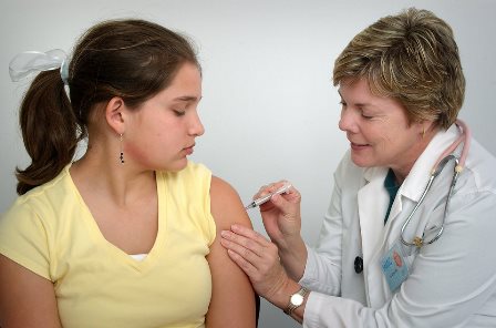Girl receiving immunization shot from nurse
