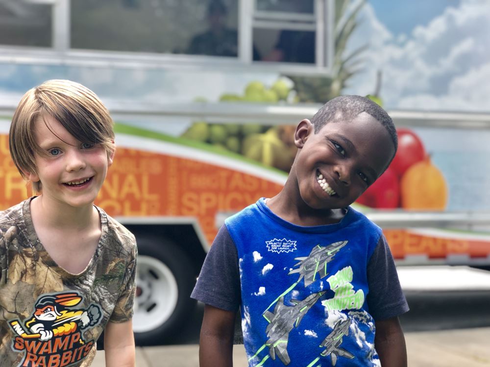2 smiling student in front of food truck