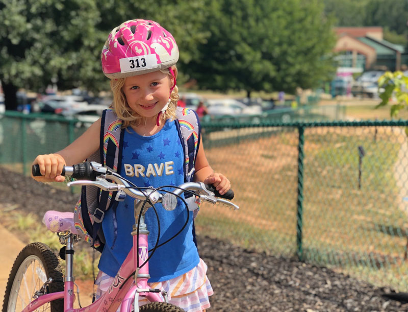Girl with bicycle wearing pink helmet