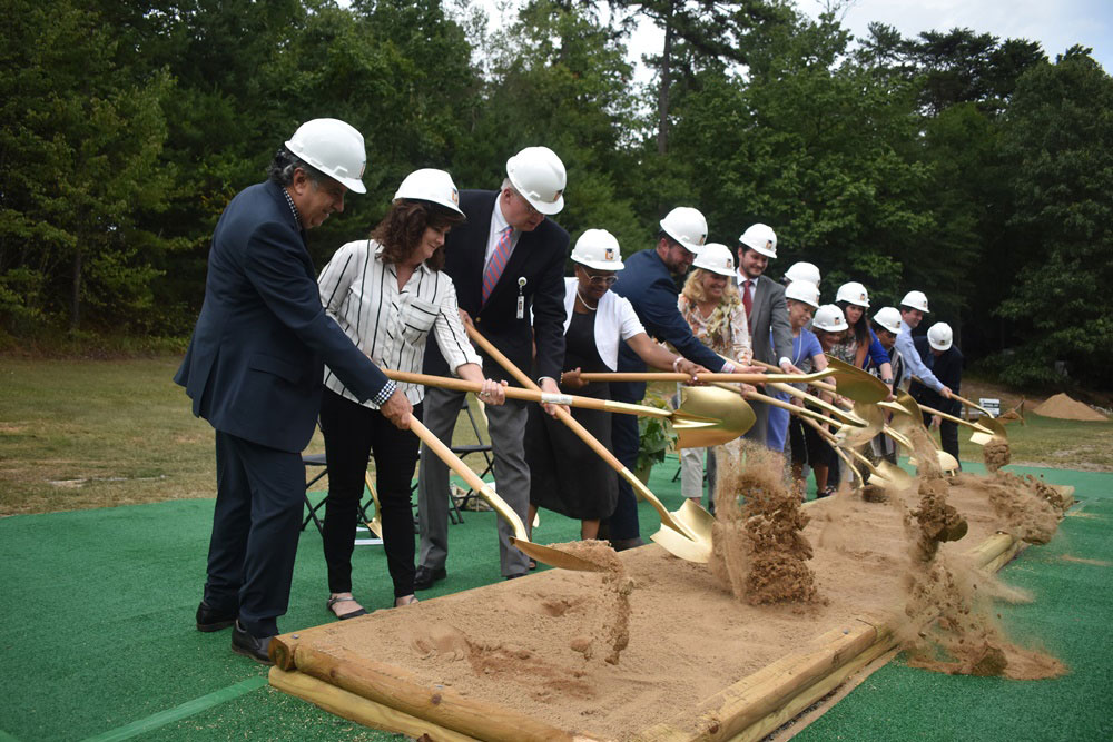 Group of people with shovels and hard hats breaking ground