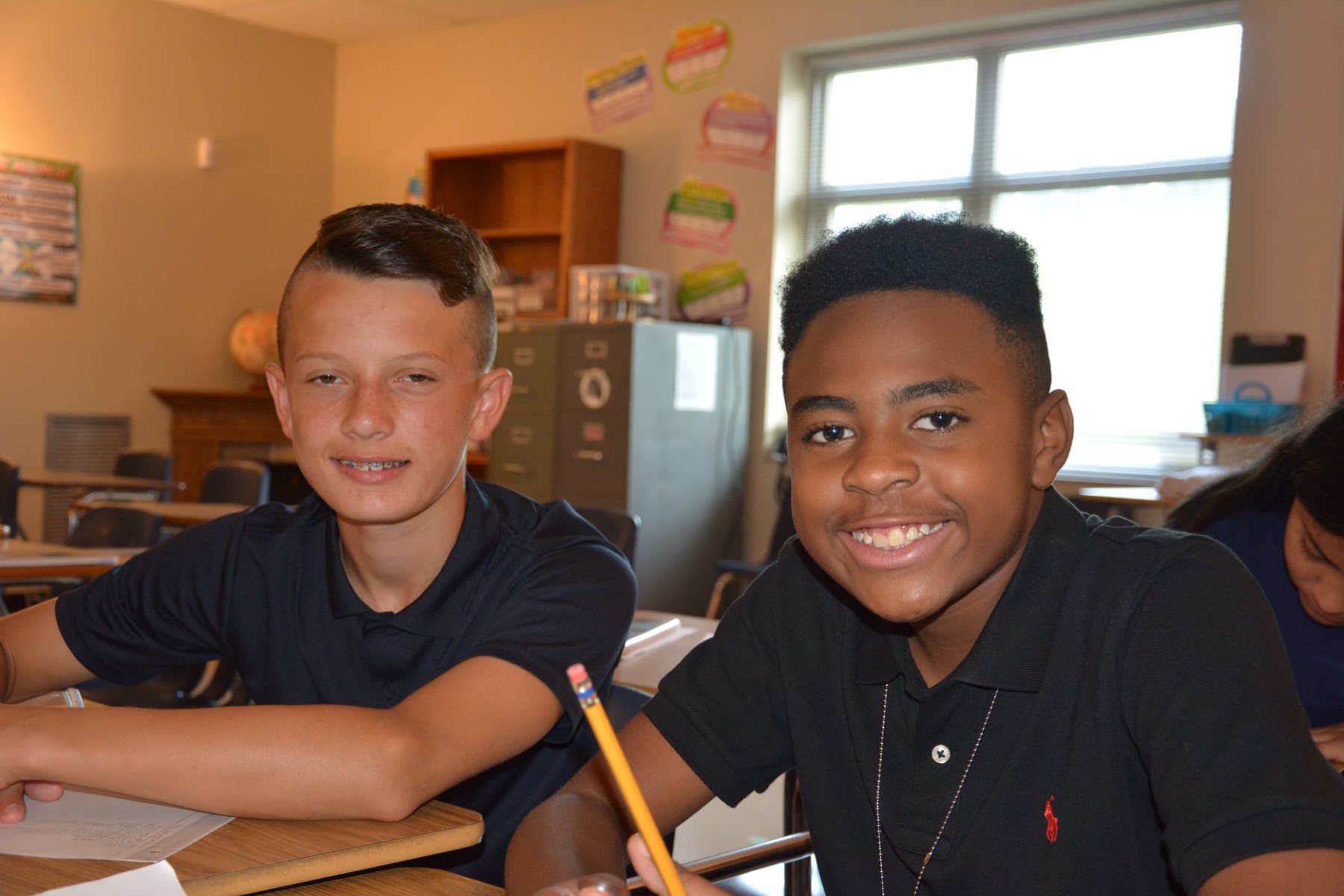 two male middle schools students at their desks in a classroom