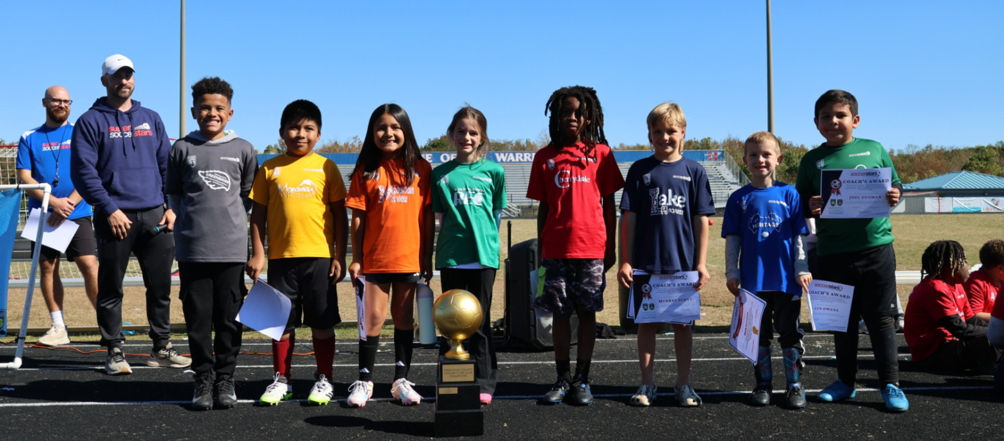 Student on a track in front of a trophy