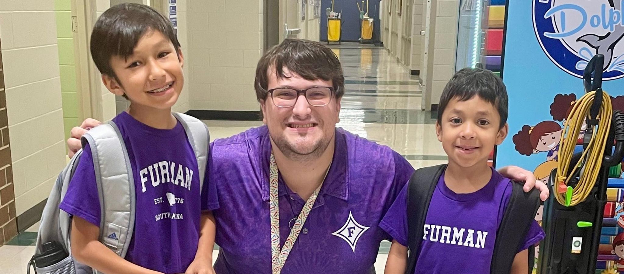 teacher and two students with Furman shirts