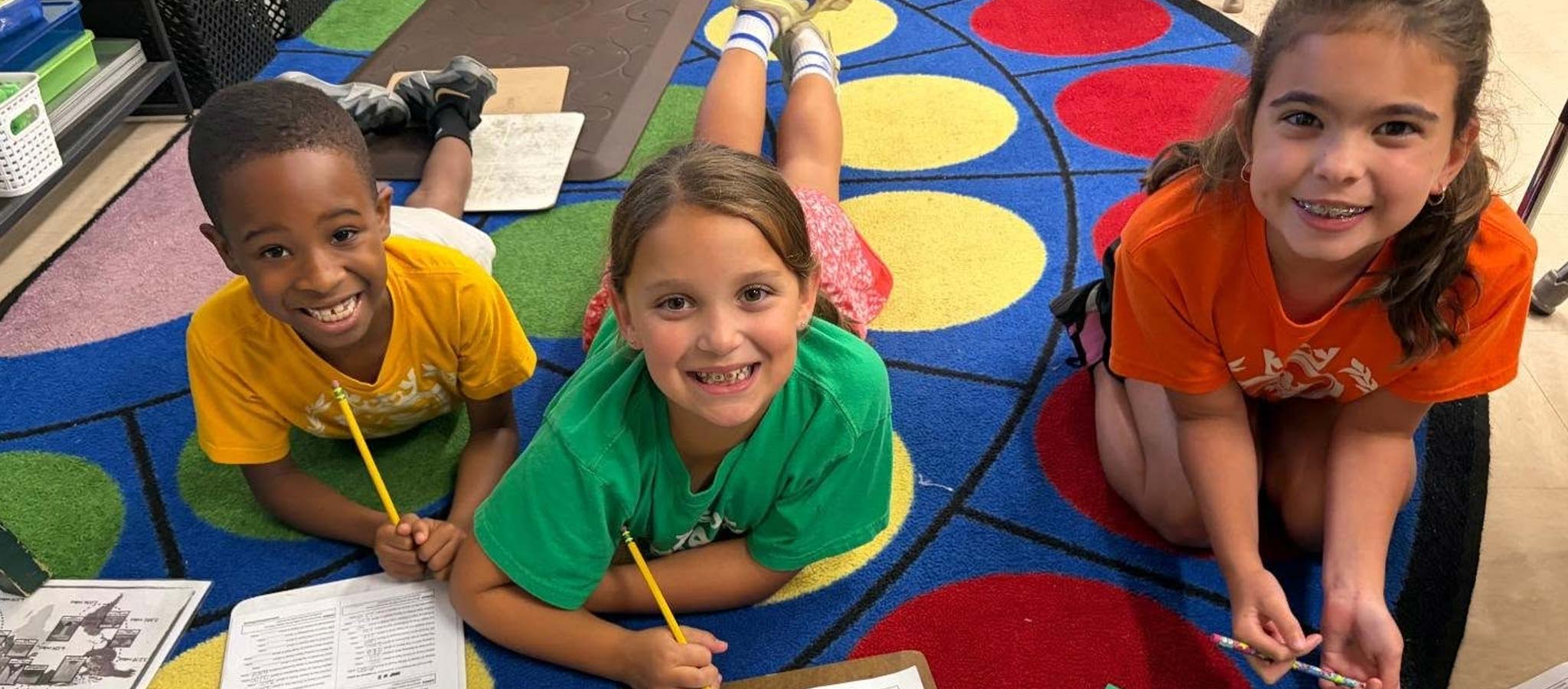3 students laying on carpeted floor doing an activity