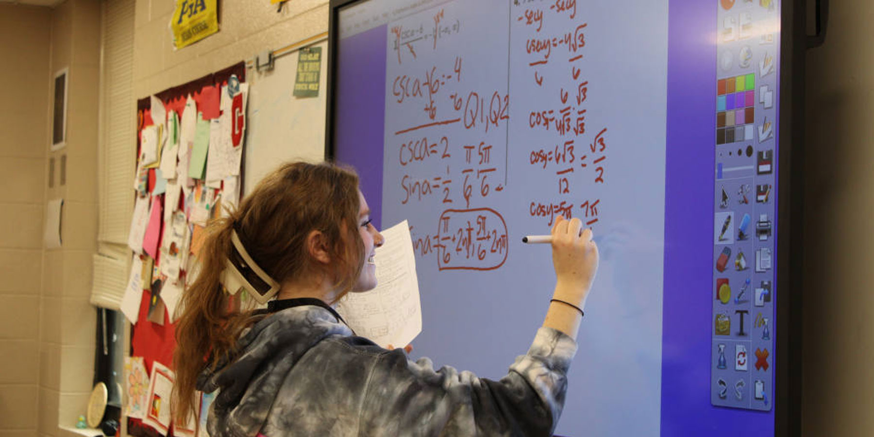 Girl working math problem on smart board