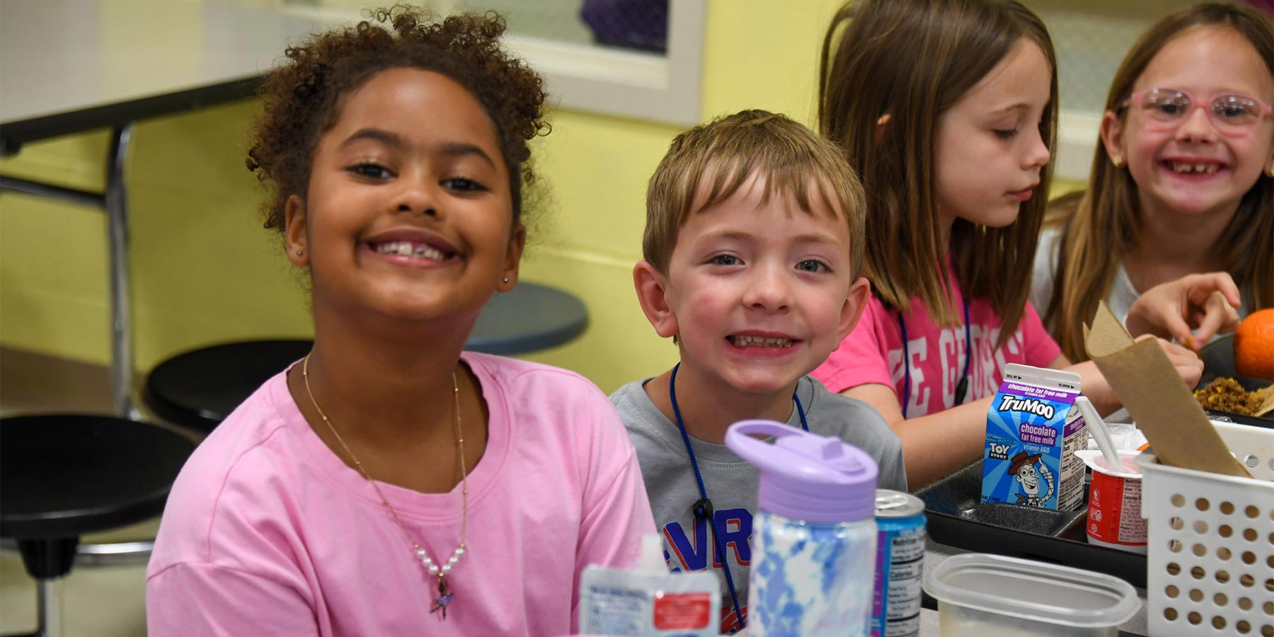 Group of elementary students at lunch - girl and boy smiling