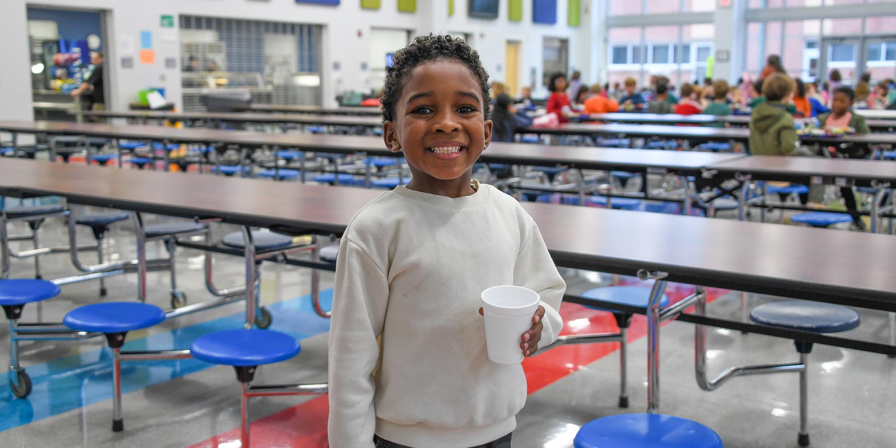 male elementary student in cafeteria smiling