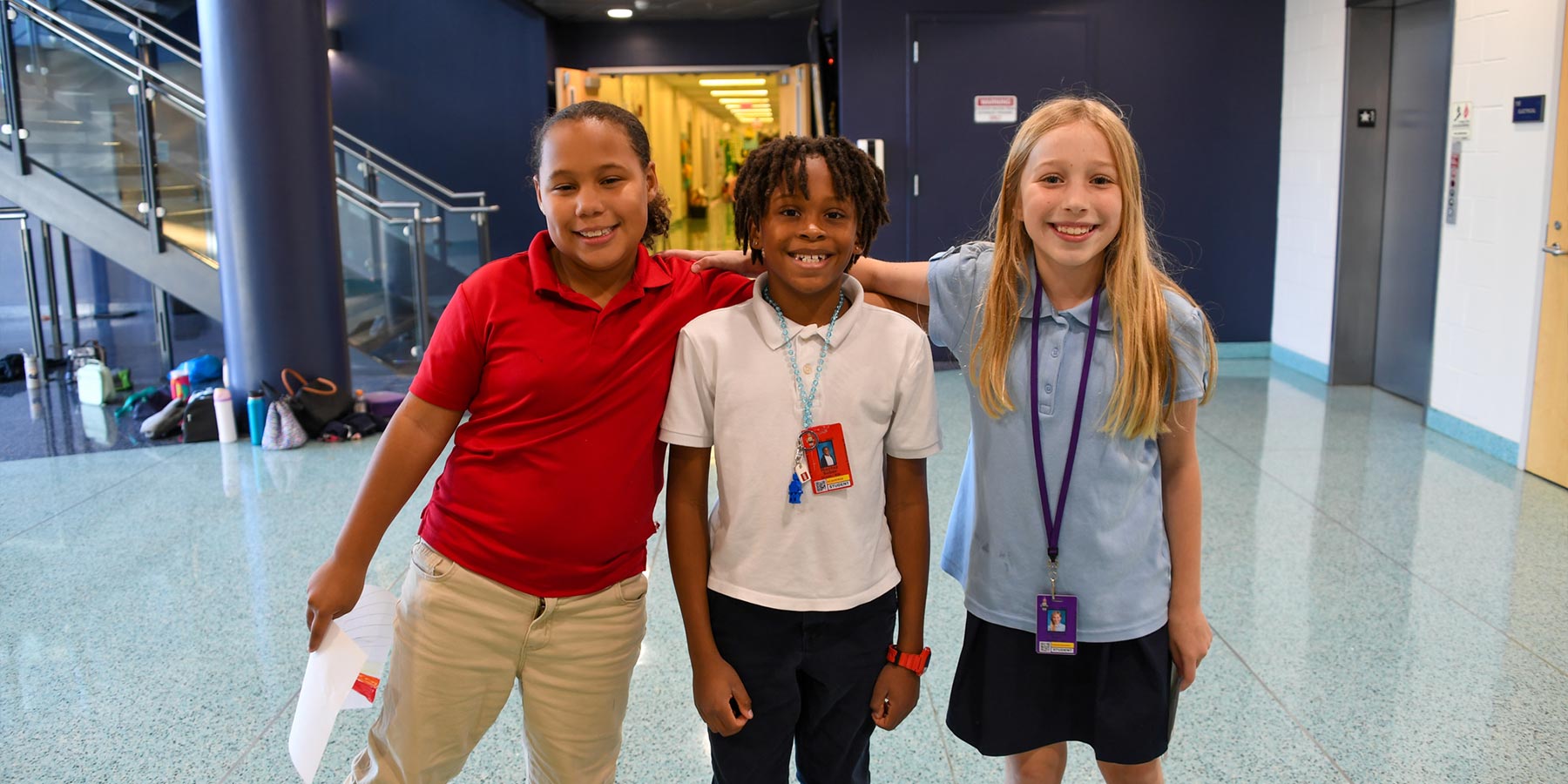 three elementary students hugging and smiling