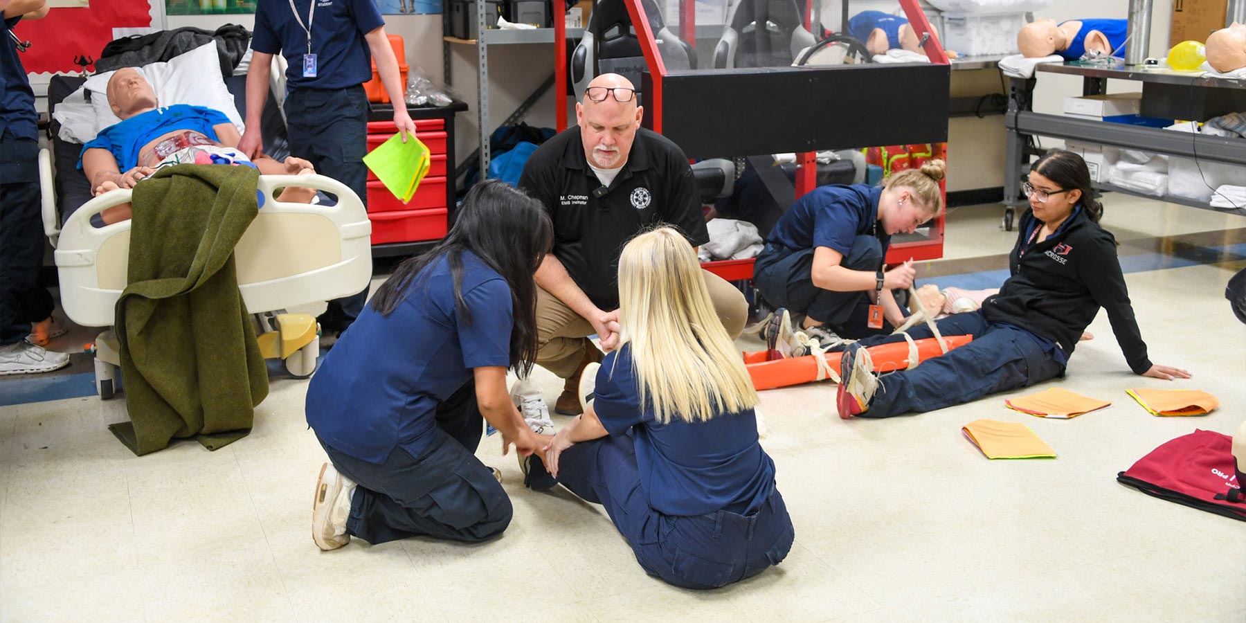 teacher working with students on first aid techniques