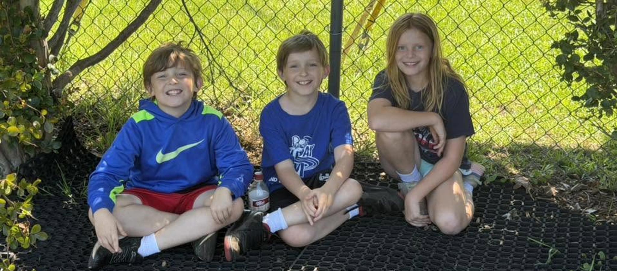 3 elementary students sitting in grass