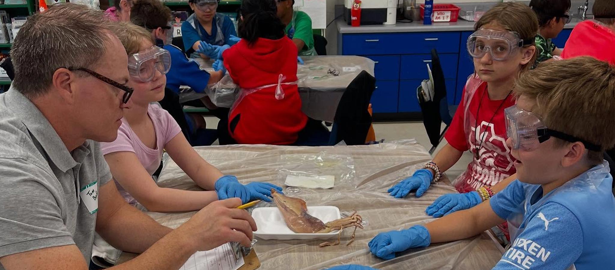 Teacher at lab table with 3 students who are dissecting a specimen