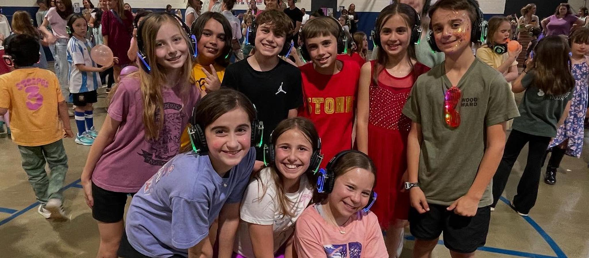 Group of nine students in gym setting wearing headphones